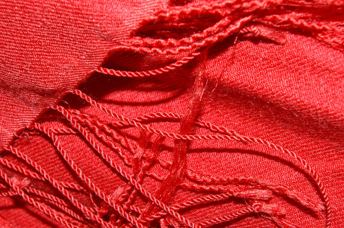 Close view of a crimson cashmere pashmina shawl with twisted fringe