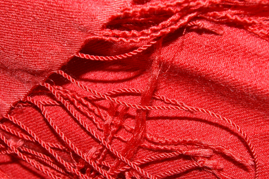 Close view of a crimson cashmere pashmina shawl with twisted fringe